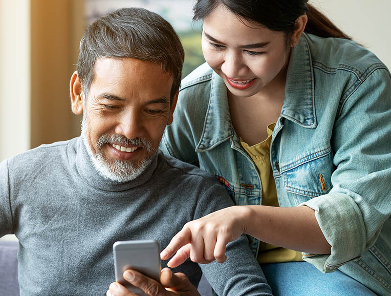 Smiling attractive stylish short beard mature asian man using smartphone
